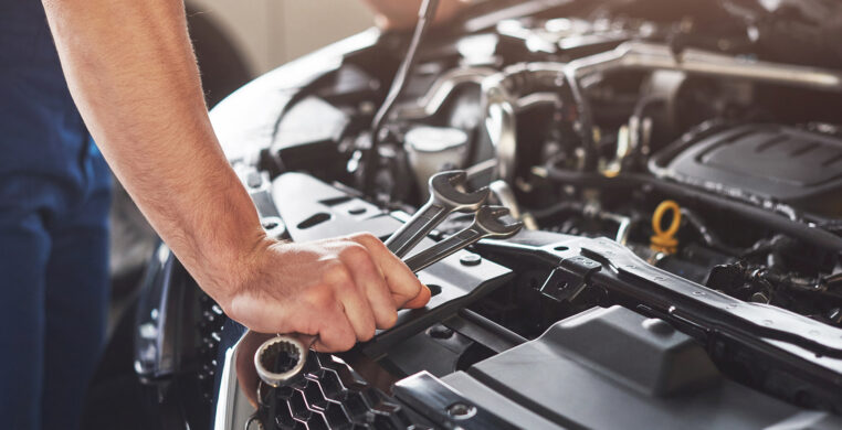 Picture showing muscular car service worker repairing vehicle.